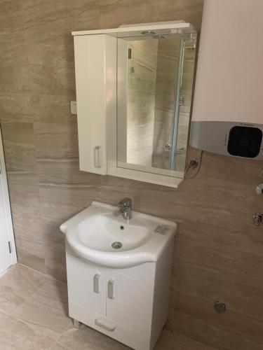 a bathroom with a white sink and a mirror at Lunde Sea View Apartment in Rafailovici