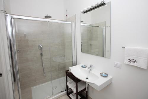 a white bathroom with a shower and a sink at Orchidea Rooms & Suites in Civitanova Marche