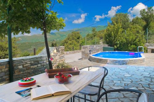 a table and chairs with a book and a pool at Pelion Goddess Villas in Agios Georgios Nilias