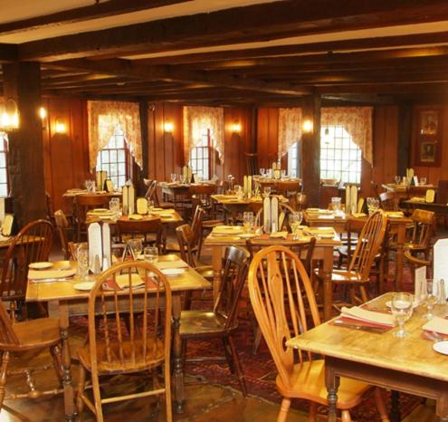 a restaurant with wooden tables and chairs and windows at Publick House Historic Inn and Country Motor Lodge in Sturbridge