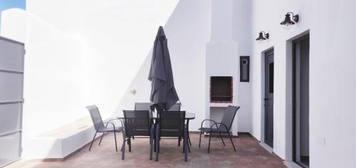 a dining room with black chairs and an umbrella at Pinheiro de Monsaraz-Casas da Colmeia T2 in Reguengos de Monsaraz