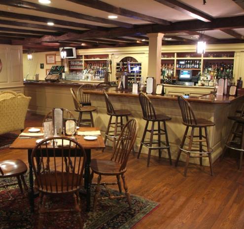 a restaurant with a bar with wooden tables and chairs at Publick House Historic Inn and Country Motor Lodge in Sturbridge