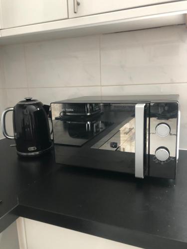 a microwave on a black counter in a kitchen at Modern Apartment in Trendy Dalston in London