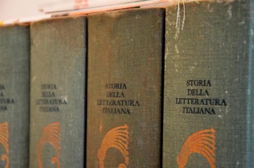 a row of books sitting on a shelf at Appartamento in palazzina storica / Oberdan Suites in Alberobello