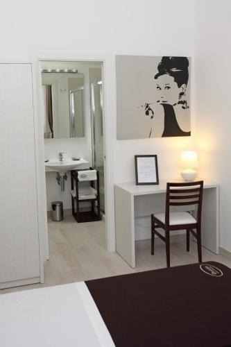 a bathroom with a sink and a desk with a chair at Orchidea Rooms & Suites in Civitanova Marche