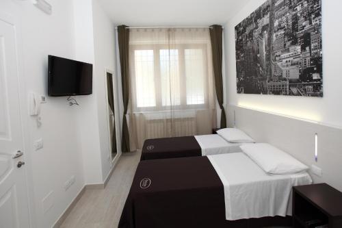 a bedroom with two beds and a tv and a window at Orchidea Rooms & Suites in Civitanova Marche
