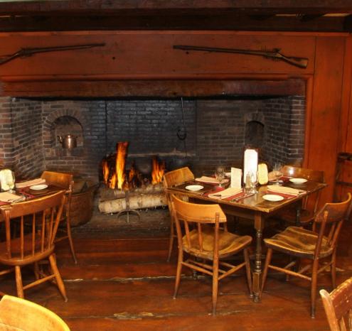 a dining room with a table and a fireplace at Publick House Historic Inn and Country Motor Lodge in Sturbridge