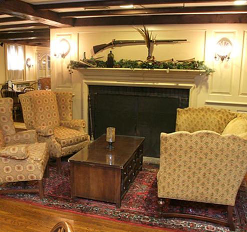 a living room with a fireplace with chairs and a table at Publick House Historic Inn and Country Motor Lodge in Sturbridge