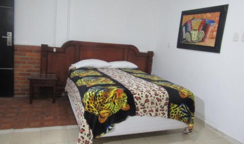 a bed with a blanket on top of it at Hotel Nuevo Tio in Valledupar