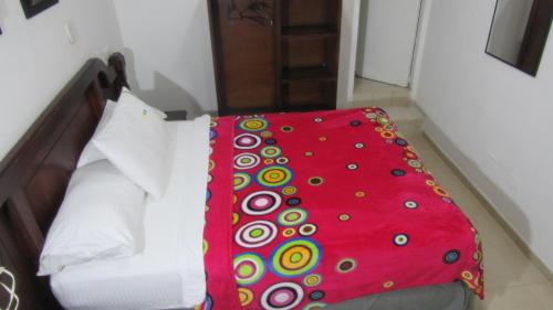 a bed with a red blanket on top of it at Hotel Nuevo Tio in Valledupar