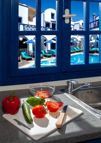 a cutting board with tomatoes and peppers on a kitchen counter at Roula Villa Studios & Apartments in Perissa