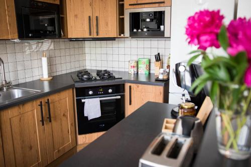 cocina con fogones y barra con flores rosas en Apartment Poruba STREET VIEW en Ostrava