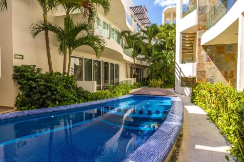 a swimming pool in front of a house at Playa Village Condo by BVR in Playa del Carmen