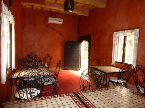 a dining room with tables and chairs and windows at Kasbah La Cigogne in Aït Ben Haddou
