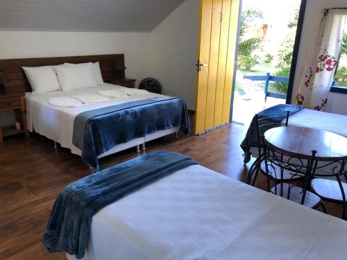 a bedroom with two beds and a table and a table at João e Maria Restaurante e Chalés in Tiradentes