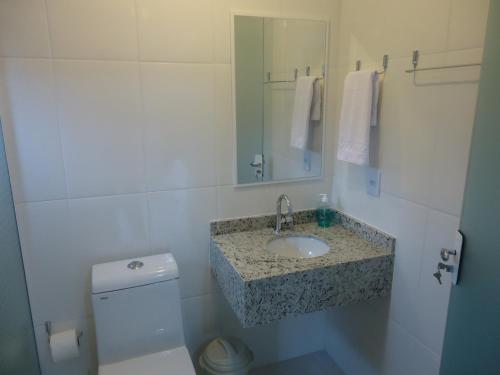 a bathroom with a sink and a toilet and a mirror at Pousada Vô Quintino in Penha