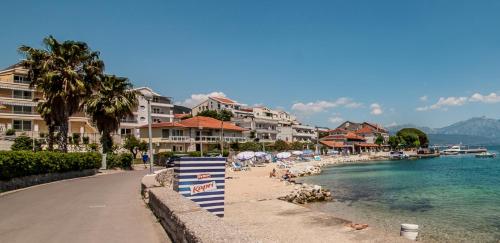 a beach with umbrellas and the water and buildings at Blue Sea in Herceg-Novi