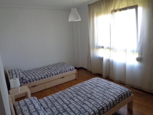 2 Betten in einem Zimmer mit Fenster und Bettröcken in der Unterkunft Casa Deva in Candás