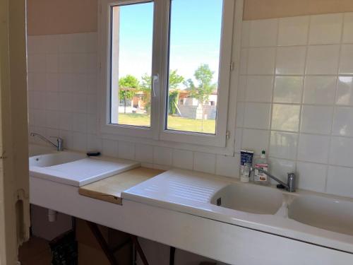 a bathroom with two sinks and a window at LE MEDOC AUX 4 VENTS in Jau-Dignac-et-Loirac