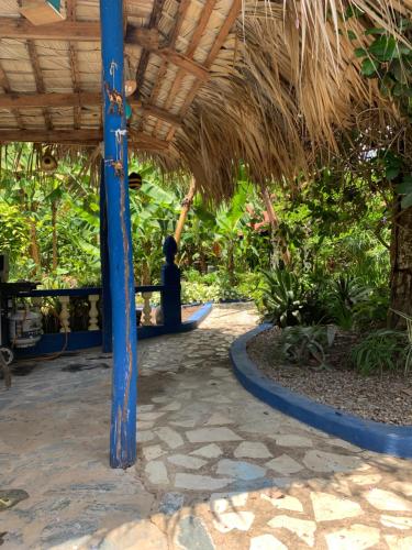 a patio with a blue pole and a straw roof at Sana El Jardin Secreto in Santiago de los Caballeros