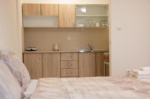 a kitchen with wooden cabinets and a bed in a room at Comfy Apartments-Ohrid in Ohrid
