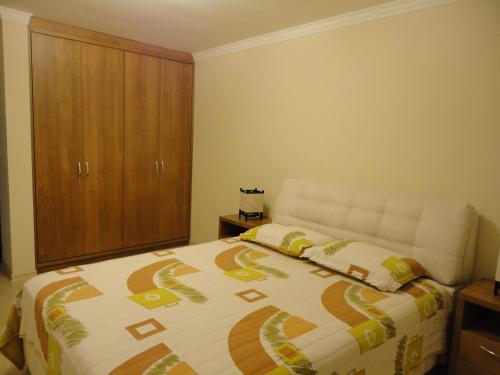 a bedroom with a bed and a wooden cabinet at Apartamento Baviera in Canela