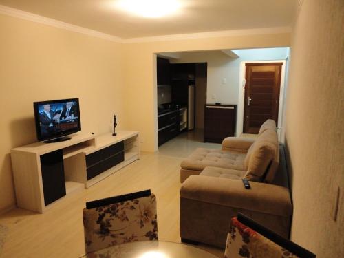 a living room with a couch and a flat screen tv at Apartamento Baviera in Canela