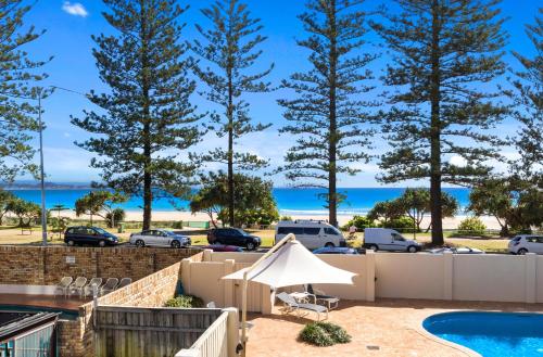 a view of the beach from a backyard with a pool and trees at Columbia Beachfront Apartments on Rainbow Bay in Gold Coast