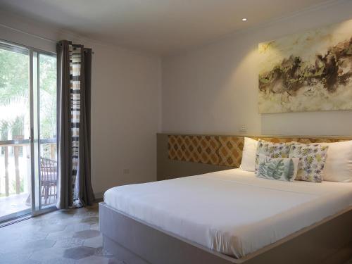 a bedroom with a large bed and a large window at Bohol Dreamcatcher Resort in Panglao Island
