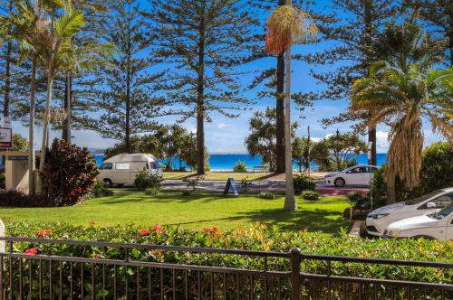 a park with palm trees and the ocean in the background at Columbia Beachfront Apartments on Rainbow Bay in Gold Coast