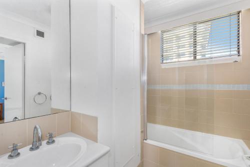 a bathroom with a tub and a sink and a mirror at Columbia Beachfront Apartments on Rainbow Bay in Gold Coast