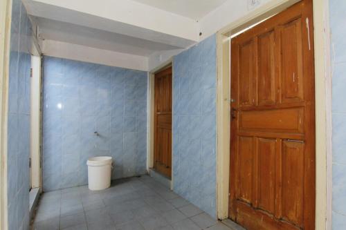 a bathroom with a toilet and a wooden door at Villa Penginapan Purnama in Bandung