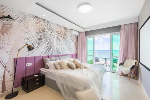 a bedroom with a purple bed with a view of the ocean at Sanya Sun Seaview Apartment in Sanya