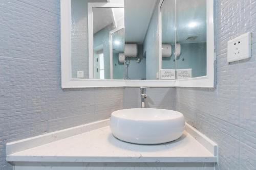 a bathroom with a white sink and a mirror at Sanya Sun Seaview Apartment in Sanya