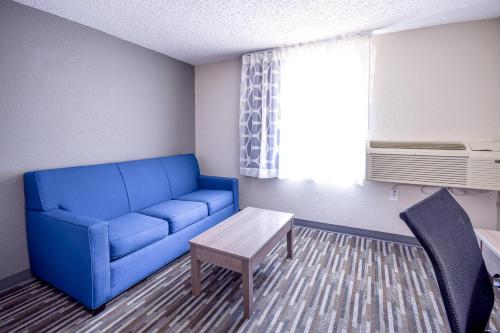 a living room with a blue couch and a table at Days Inn & Suites by Wyndham Wisconsin Dells in Wisconsin Dells