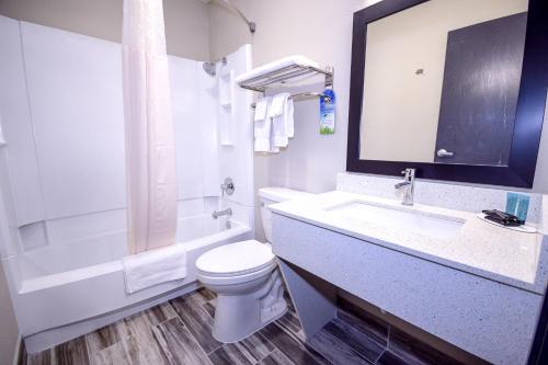 a white bathroom with a toilet and a sink at Days Inn & Suites by Wyndham Wisconsin Dells in Wisconsin Dells
