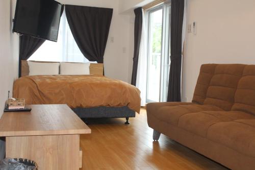 a living room with a bed and a couch at M´s Stay Okinawa in Chatan