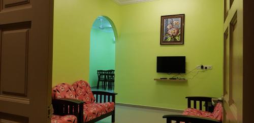 a living room with two chairs and a television at Teratak Nipah Homestay Teluk Nipah Pangkor in Pangkor