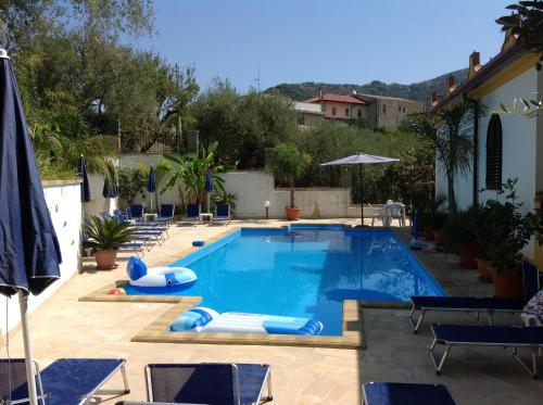 a large swimming pool with chairs and an umbrella at Villafiorita in Gioiosa Marea