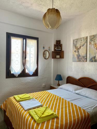 a bedroom with a bed with a yellow and white striped blanket at Villa Fourka 2 on the beach in Fourka
