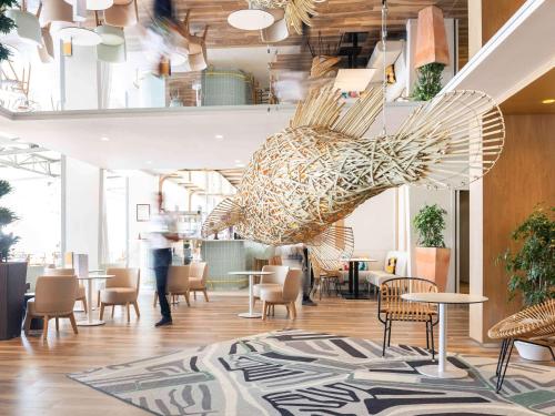 un hall avec des tables et des chaises et une grande sculpture dans l'établissement Novotel Thalassa Ile d'Oléron, à Saint-Trojan-les-Bains