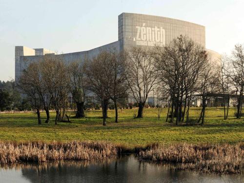 a building with a sign on it next to a body of water at ibis Nantes Saint Herblain in Saint-Herblain