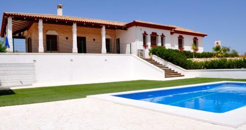 a villa with a swimming pool in front of a house at Casa Rural la Serrana in La Carlota