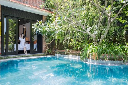 a woman is standing in the window of a house with a swimming pool at MAI Villa Da Nang in Da Nang