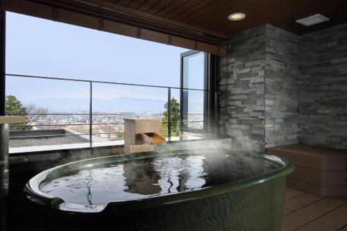 a hot tub in a room with a large window at Shoho in Matsumoto