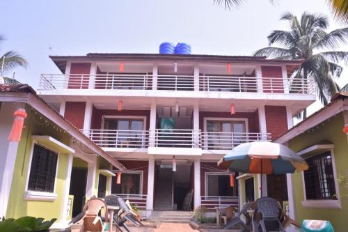 a large pink building with an umbrella and chairs at Vamoose Gajanan in Malvan