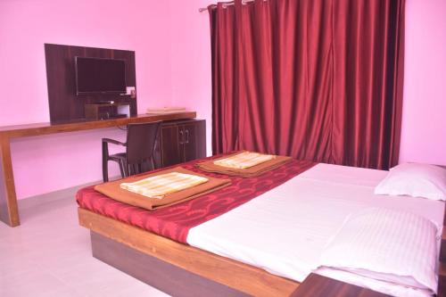 a bedroom with a bed with a desk and a red curtain at Vamoose Gajanan in Malvan