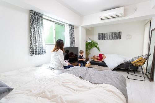 a woman and child sitting on a bed in a living room at Sakura Cross Hotel Ueno Iriya in Tokyo
