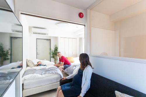 two children sitting on beds in a room with a mirror at Sakura Cross Hotel Ueno Iriya in Tokyo