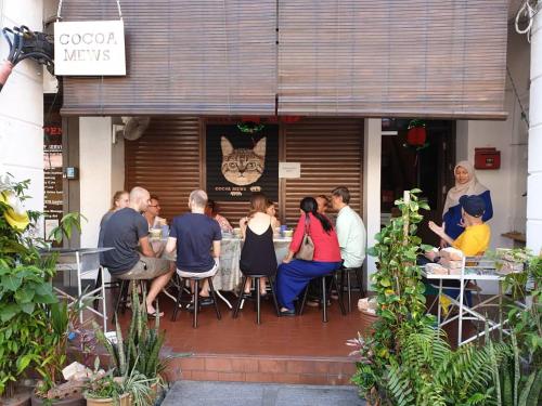 a group of people sitting at a table outside a restaurant at Cocoa Mews Cafe and Homestay in George Town